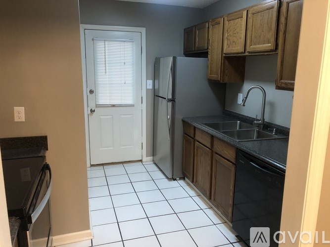 A kitchen with a white door, black appliances, and wooden cabinets.