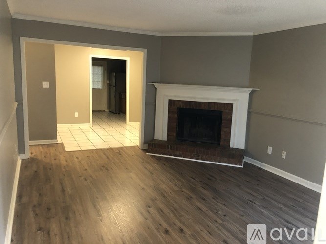 A room with a fireplace and a doorway leading to another room.
