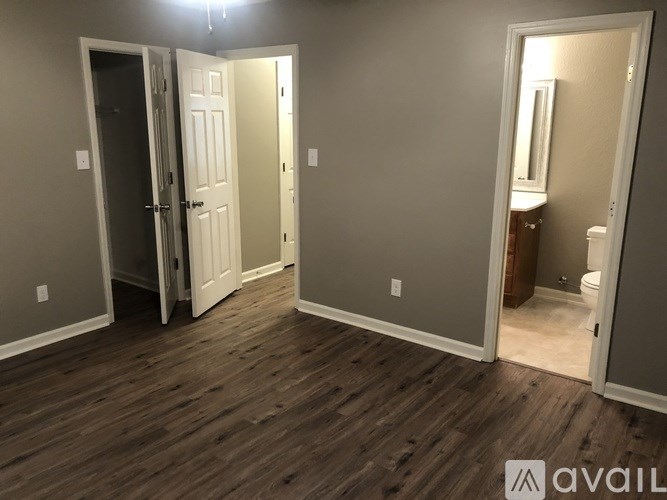 A room with a wooden floor and two doors, one of which is open.