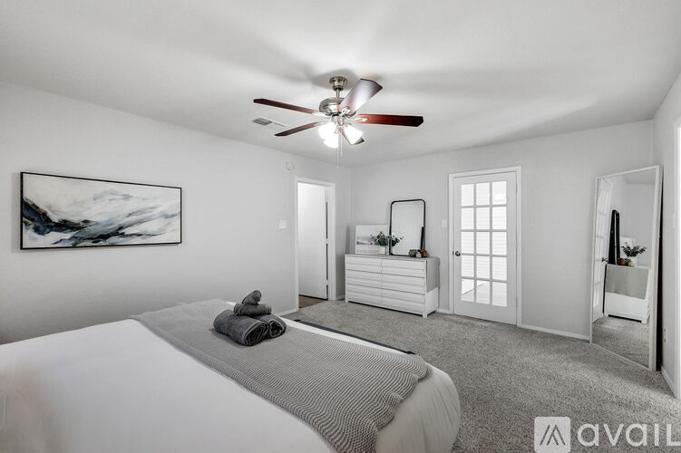 A bedroom with a large bed and a ceiling fan.