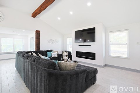 A modern living room with a grey couch and a flat screen TV mounted on the wall.