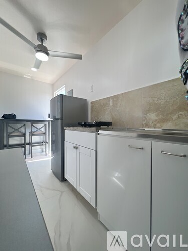 A kitchen with white cabinets and a refrigerator.