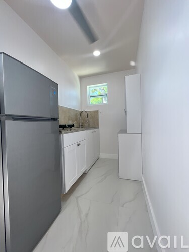 A kitchen with white cabinets and a grey fridge.