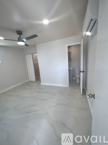 A room with a ceiling fan and marble flooring.