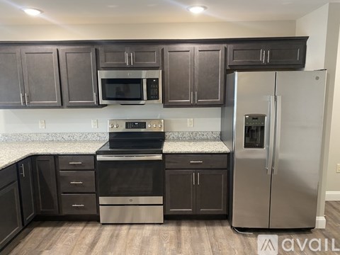 A kitchen with dark brown cabinets and stainless steel appliances.
