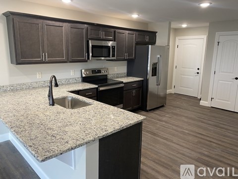 A kitchen with dark brown cabinets and a granite countertop.