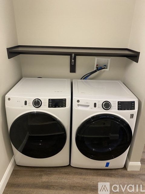 Two white front loading washing machines in a small laundry room.