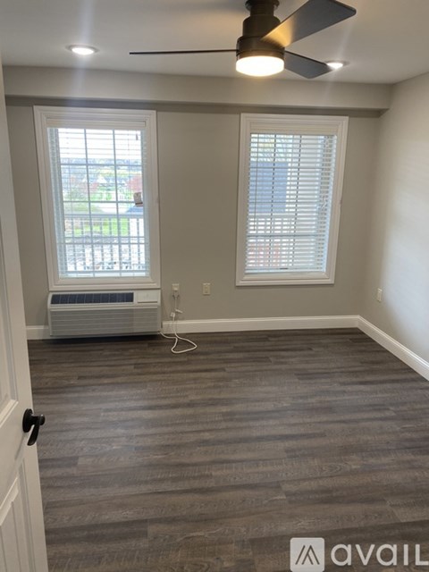 A room with a ceiling fan and a window with blinds.