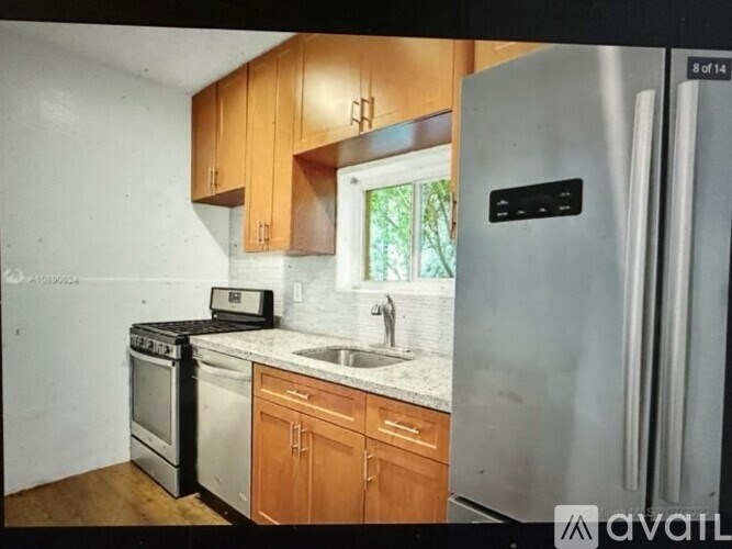 A kitchen with wooden cabinets and a stainless steel refrigerator.