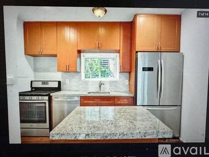 A kitchen with a granite countertop and wooden cabinets.