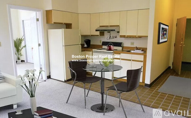 A kitchen area with a table and chairs in the foreground and a dining area in the background.
