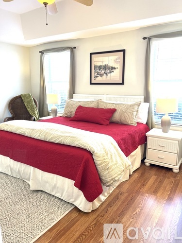 A bedroom with a red and white bed and a ceiling fan.