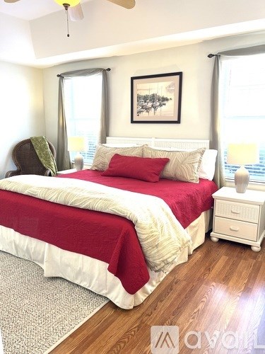 A bedroom with a red and white bed and a ceiling fan.