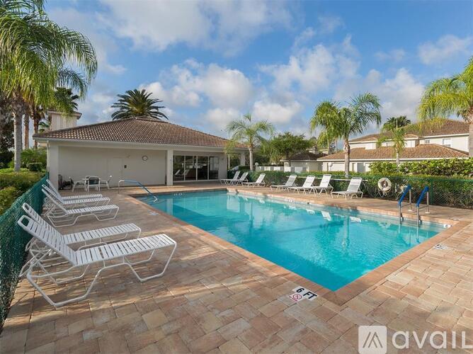 A pool with chairs around it and a house in the background.