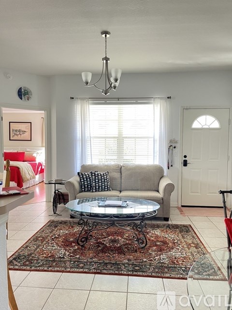 A living room with a grey couch and a glass coffee table.