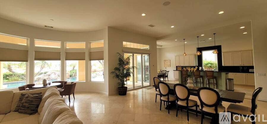 A patio with a table and chairs overlooking a pool.