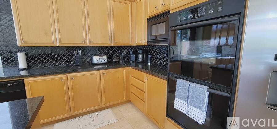 A kitchen with wooden cabinets and black countertops.