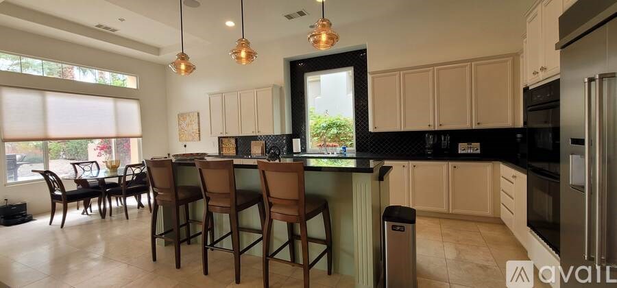 A kitchen with a black countertop and brown chairs.