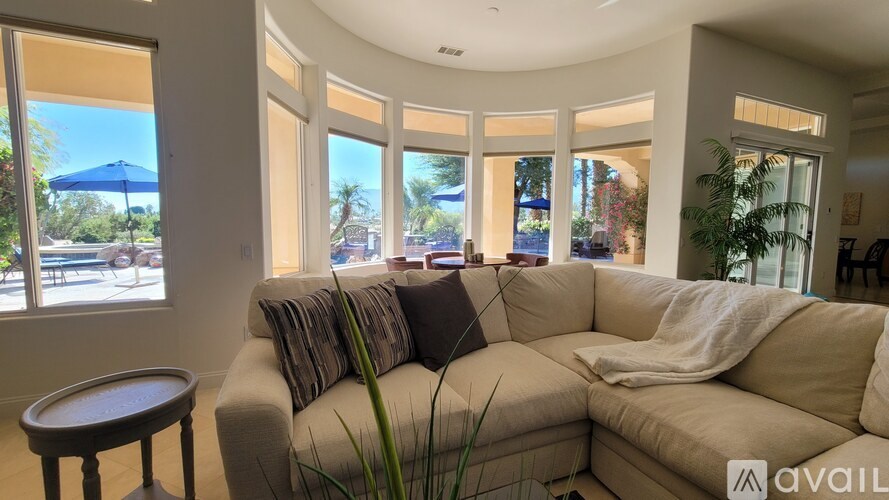 A living room with a beige couch and a round table.