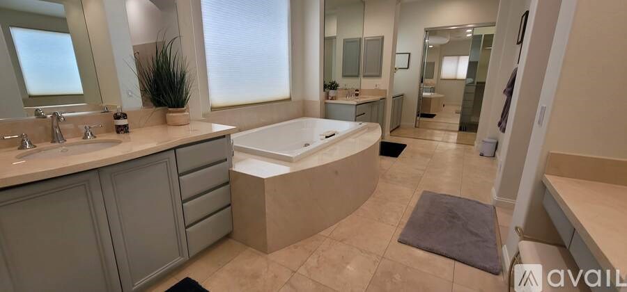 A bathroom with a large mirror, sink, and bathtub.