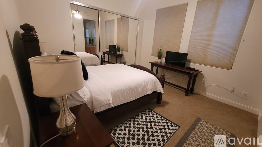 A bedroom with a bed, a desk with a laptop, and a lamp.