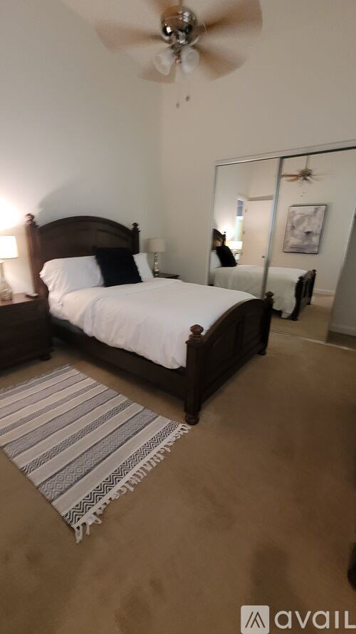 A bedroom with a bed, a rug, and a ceiling fan.