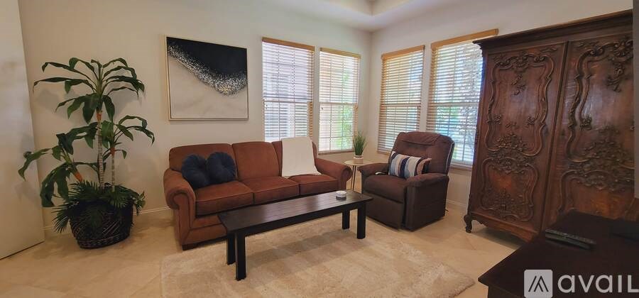 A living room with a brown couch, a wooden cabinet, and a potted plant.