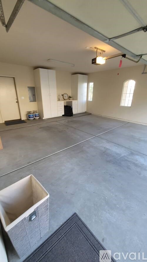 A large empty room with a concrete floor and a window on the wall.