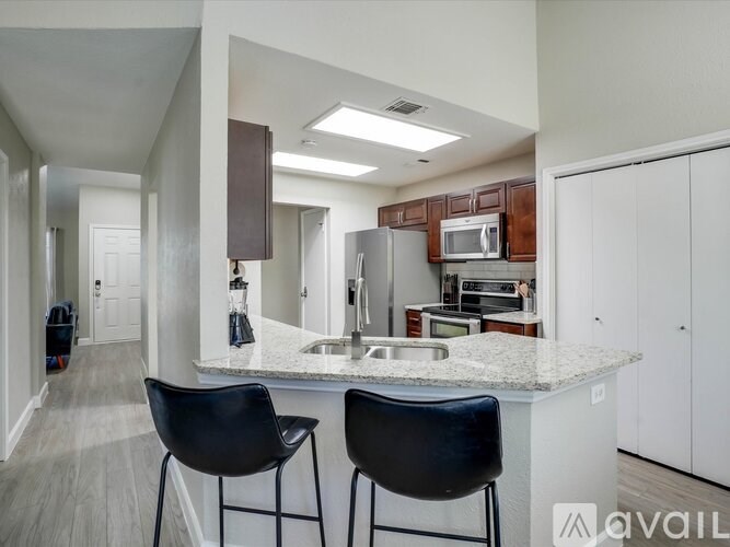 A kitchen with a white countertop and black barstools.