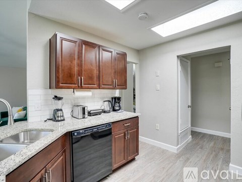 A kitchen with wooden cabinets and a black dishwasher.