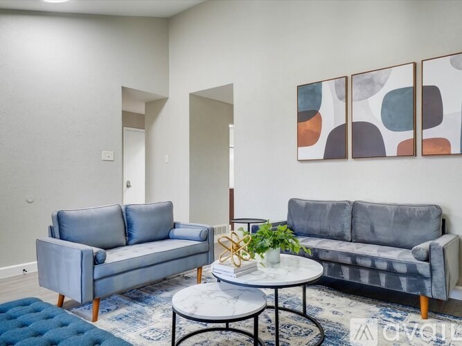 A living room with a grey couch, a blue ottoman, and a white coffee table.