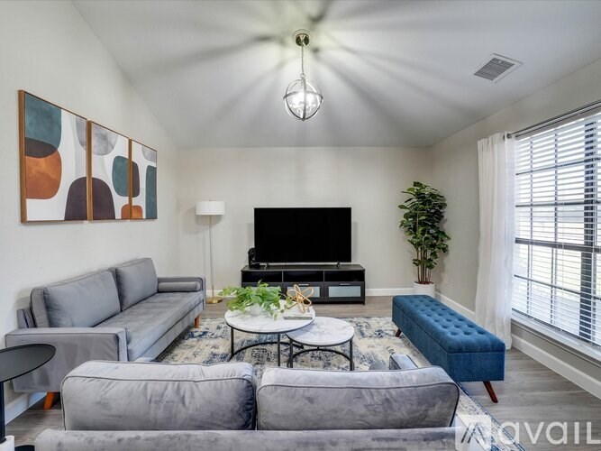 A living room with a grey sofa, a black television, and a ceiling fan.