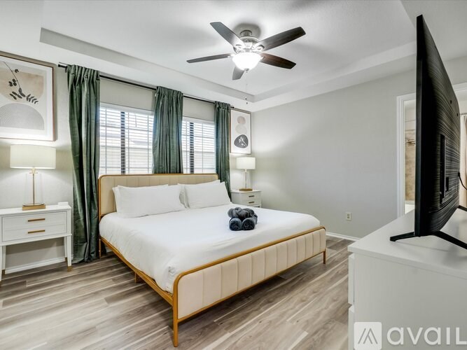 A bedroom with a bed, a ceiling fan, and a television.
