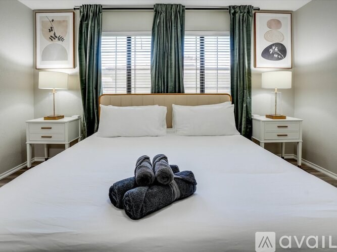 A neatly made bed with a white comforter and two folded towels on top.