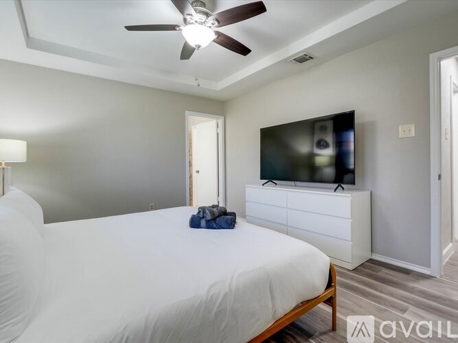 A bedroom with a bed, a ceiling fan, and a television.