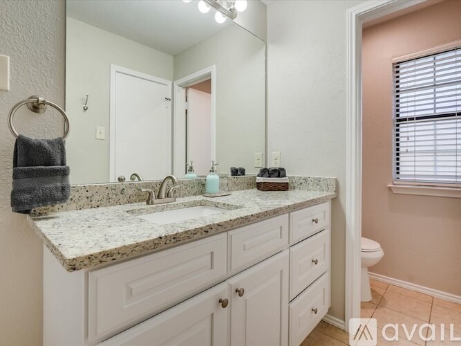 A bathroom with a granite countertop and a towel hanging on the ring.