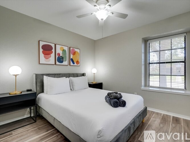 A bedroom with a bed, two lamps, and a ceiling fan.