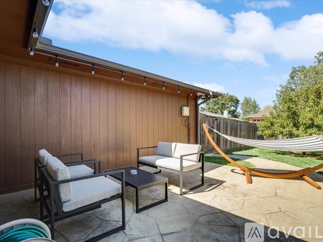A patio with a hammock and chairs.