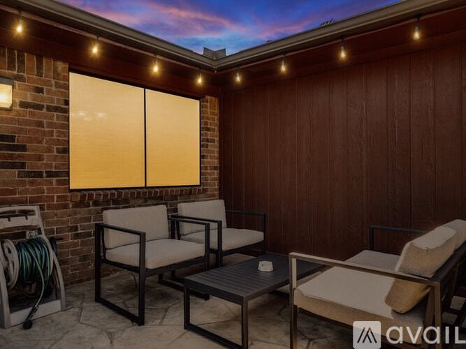 A patio with a table, chairs and lights.