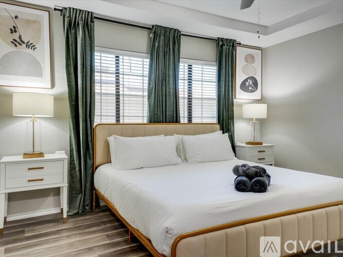 A bedroom with a large bed, a nightstand with a lamp, and a wall-mounted fan.