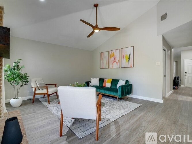 A living room with a white sofa, a wooden table, a ceiling fan, and a painting on the wall.