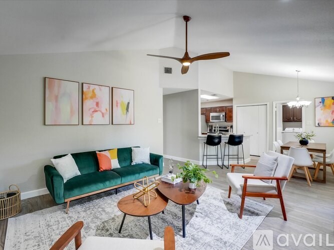 A living room with a green couch, a coffee table, and a ceiling fan.