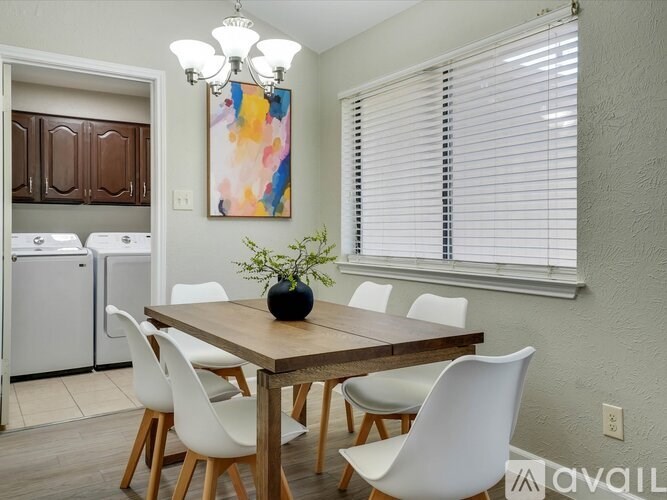 A dining room with a wooden table and white chairs.