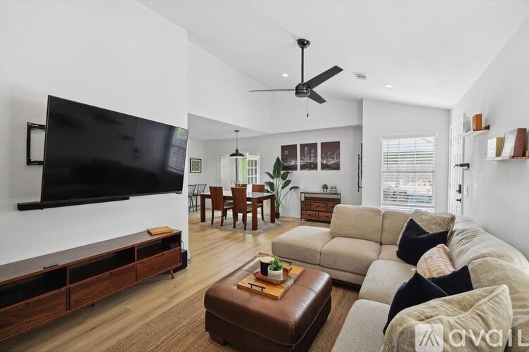 A living room with a large couch, a flat screen TV, and a ceiling fan.