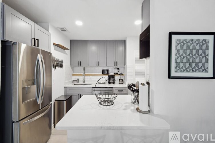 A modern kitchen with a refrigerator, sink, and cabinets.