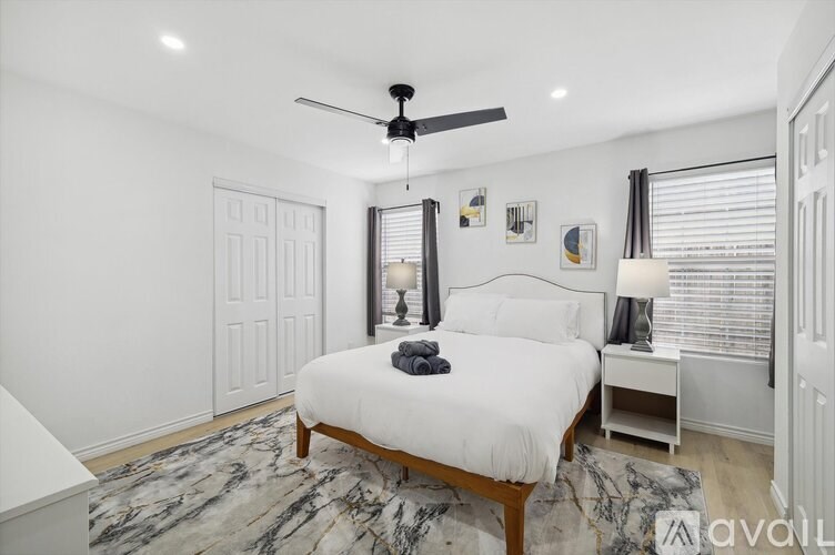 A bedroom with a large bed and a ceiling fan.