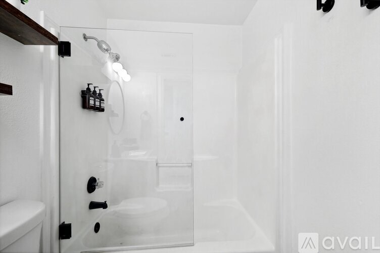 A white bathroom with a glass shower door and a white toilet.