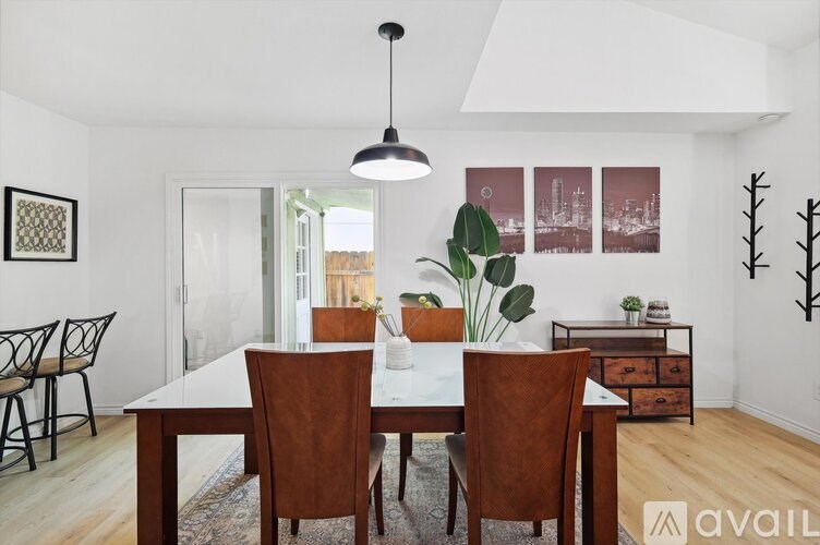 A dining room with a white table and brown chairs.