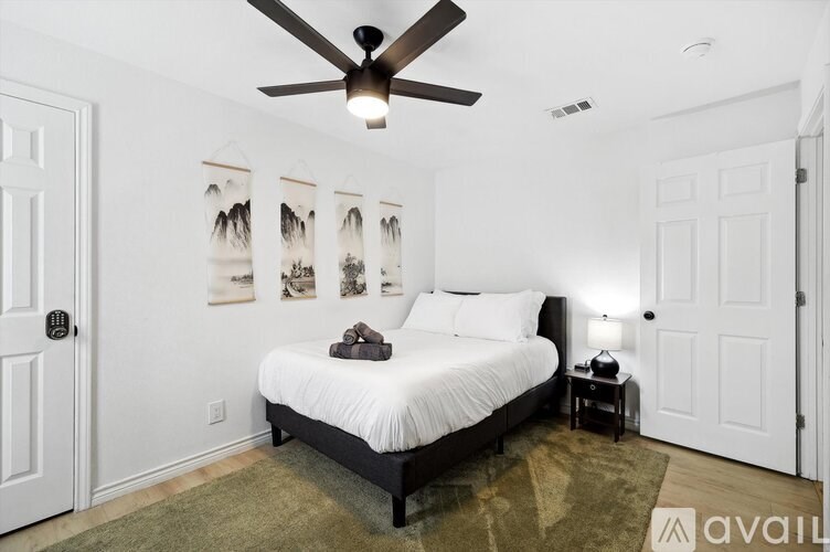 A bedroom with a bed, a ceiling fan, and pictures on the wall.