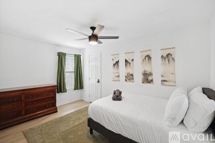 A bedroom with a bed, dresser, and pictures on the wall.